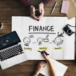 Finance poster and laptop on a wood desk