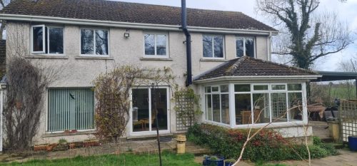 wide view of house featuring white upvc sliding patio doors and white upvc windows with white upvc tiled roof conservatory