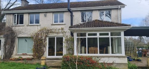 wide view of house featuring white upvc sliding patio doors and white upvc windows with white upvc tiled roof conservatory